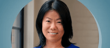 Professional headshot of a woman in a blue top smiling warmly against a soft-focus background
