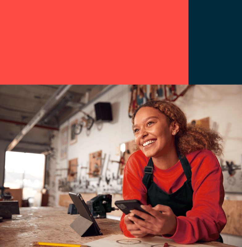 A woman using her phone at a cafe and smiling at a customer